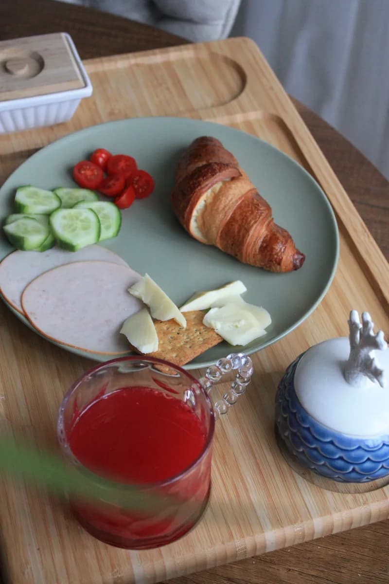 Imagen de ejemplo de BookNoFees: bandeja de desayuno con un croissant, verduras y jugo