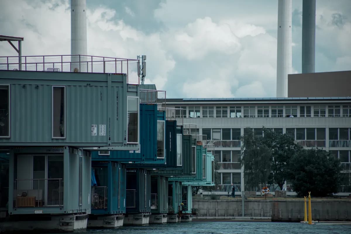 Imagen de ejemplo de BookNoFees: Edificios de contenedores de colores con un muelle junto al agua