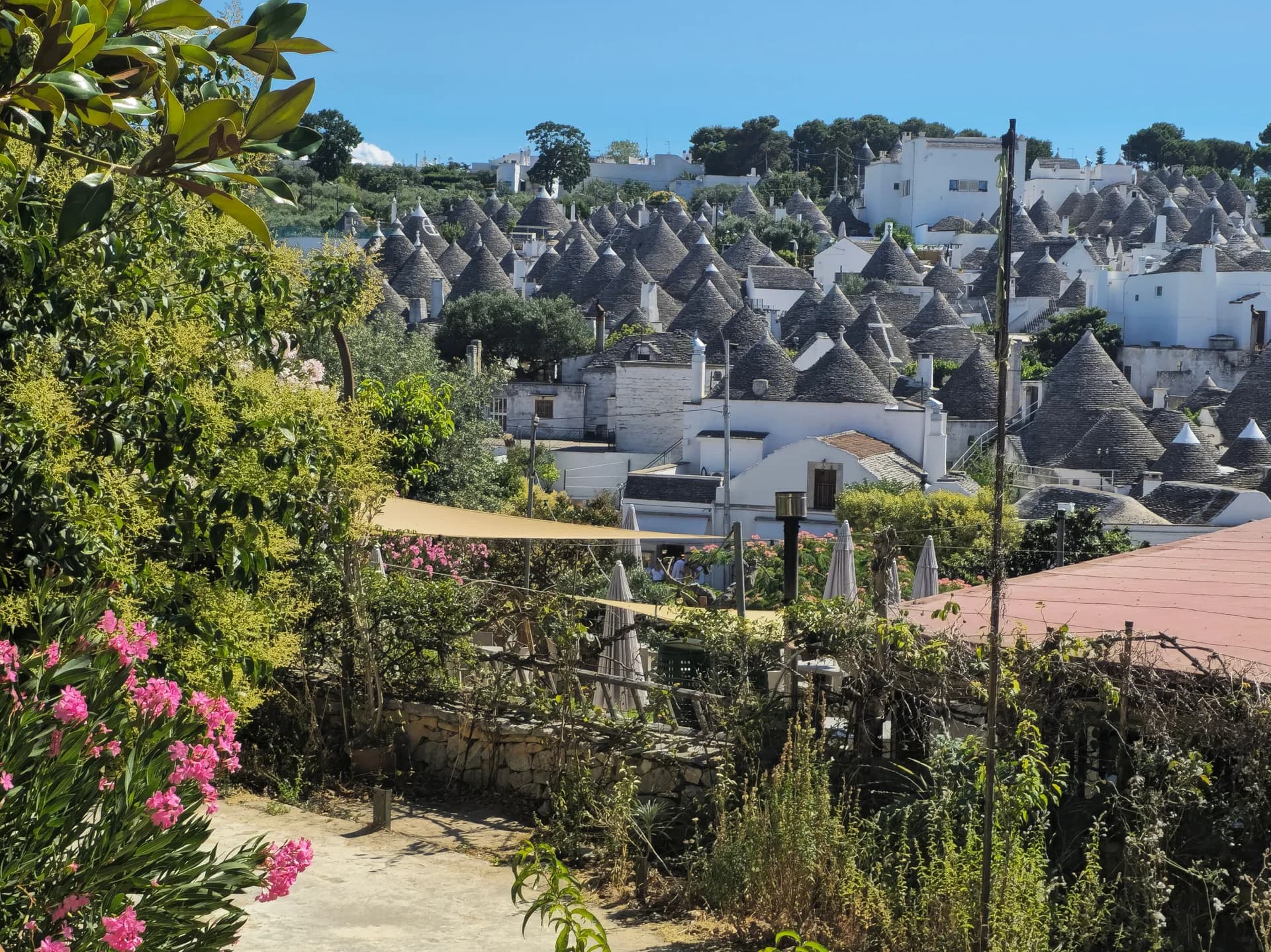 Imagen de ejemplo de BookNoFees: Trulli blancos con techos cónicos de piedra y jardines