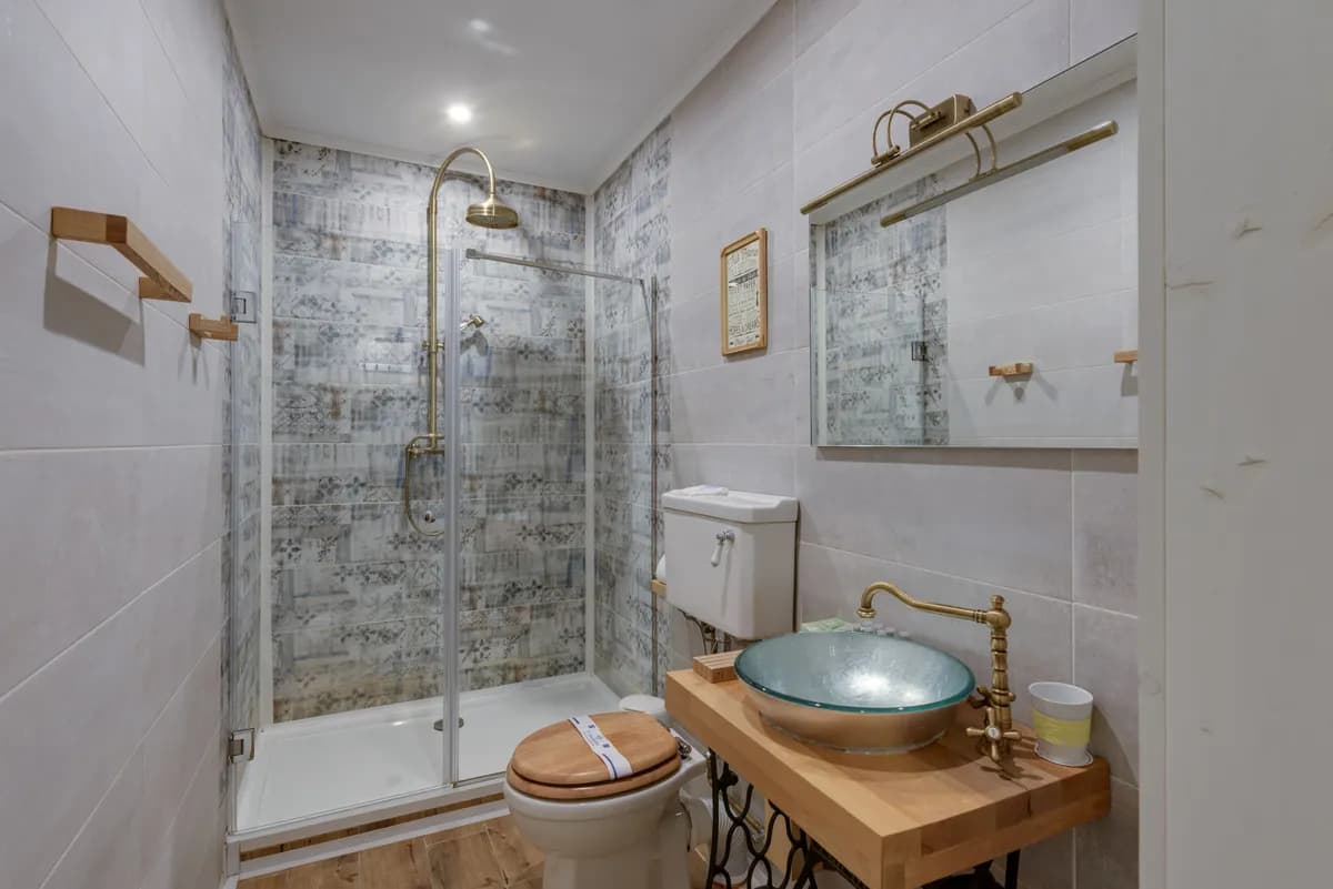 Imagen de ejemplo de BookNoFees: baño con ducha de vidrio y lavabo sobre un armario de madera