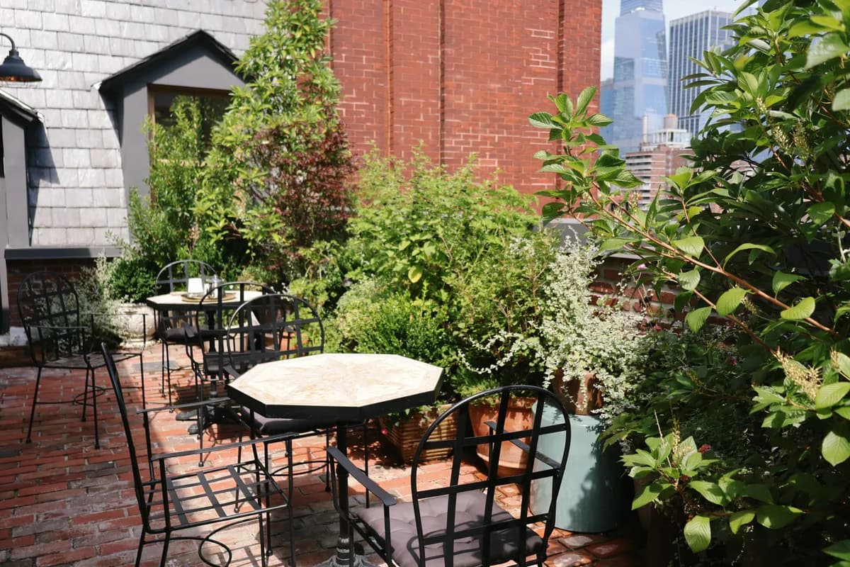 Imagen de ejemplo de BookNoFees: Terraza ajardinada con mesas redondas y sillas