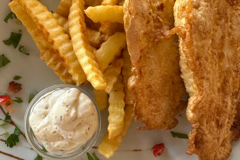 BookNoFees: Foto de ejemplo: Filetes de pescado rebozados con papas fritas onduladas y un tazón pequeño de salsa
