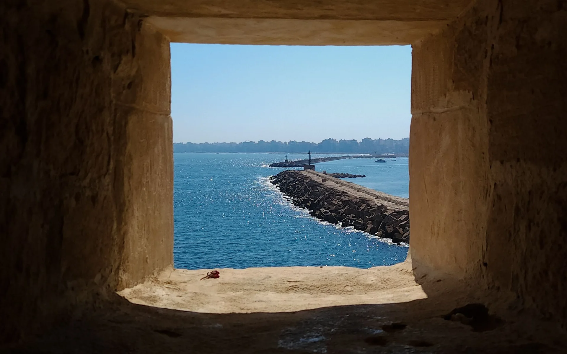 Vista al mar a través de una ventana histórica de piedra en Alejandría