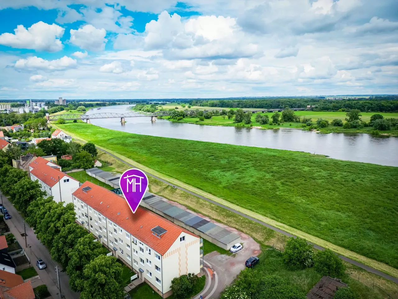 BookNoFees: renta vacacional en Barby, Alemania – Vista aérea de un edificio de apartamentos con techo rojo cerca de un río y un puente