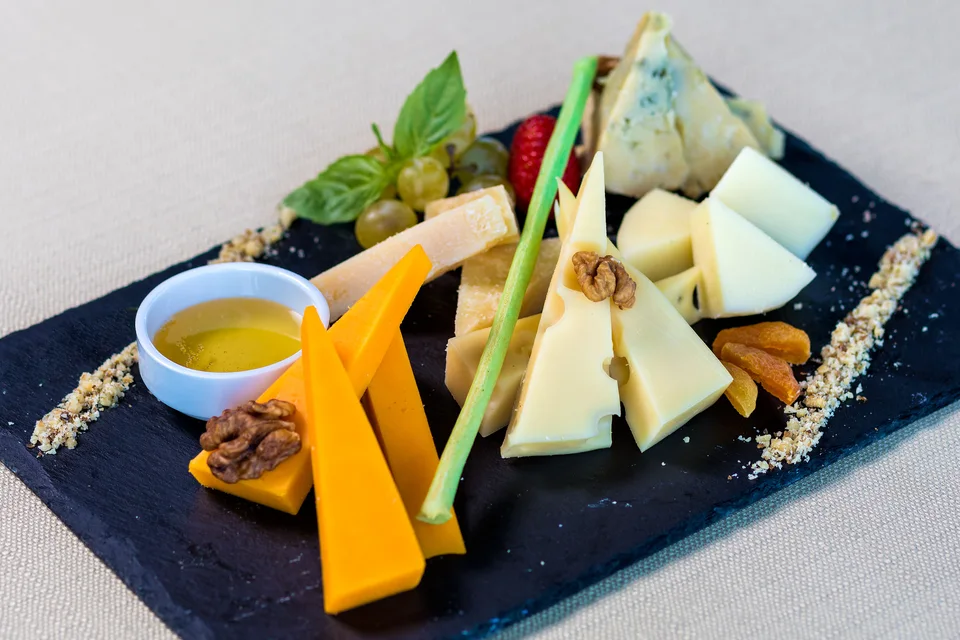 Foto de ejemplo: Surtido de quesos con frutas y nueces en una tabla de servir