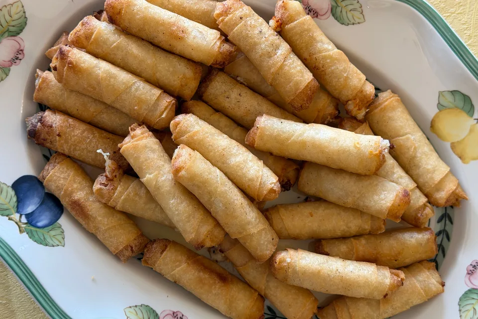 Foto de ejemplo: Rollitos de primavera dorados y fritos en un plato estampado