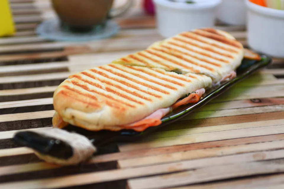 Foto de ejemplo: Un panini tostado con marcas de la parrilla en un plato oscuro