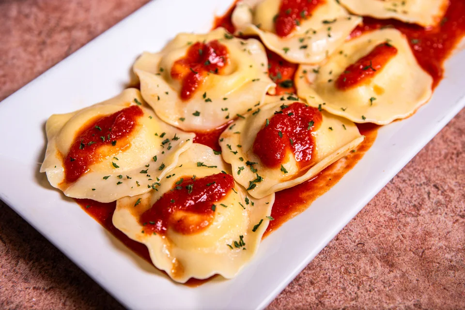 Foto de ejemplo: Raviolis con salsa de tomate y hierbas en un plato blanco